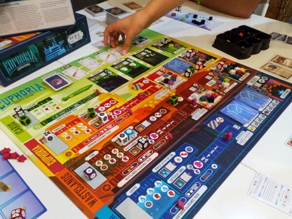 Partita in corso al gioco da tavolo Euphoria: Build a Better Dystopia, con dadi e segnalini colorati sul tabellone